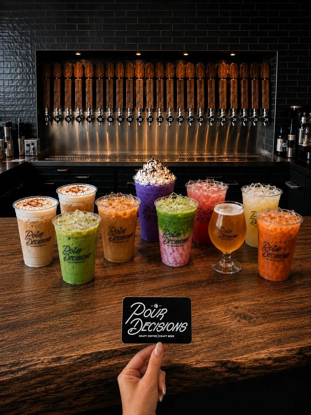 A colorful lineup of Pour Decisions Craft signature coffee, matcha, and fruit drinks on the bar in front of the craft-beer tap wall